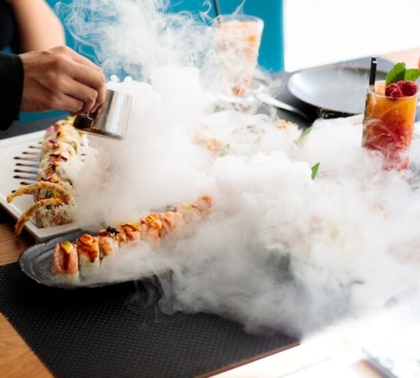 A person holding utensils over a plate of sushi, ready to indulge in the delicious Japanese cuisine.
