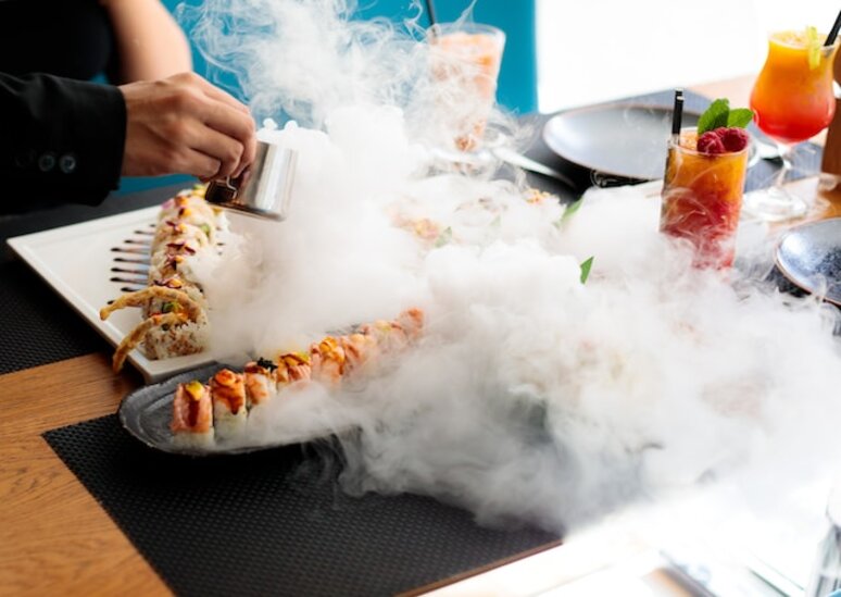 A person holding utensils over a plate of sushi, ready to indulge in the delicious Japanese cuisine.